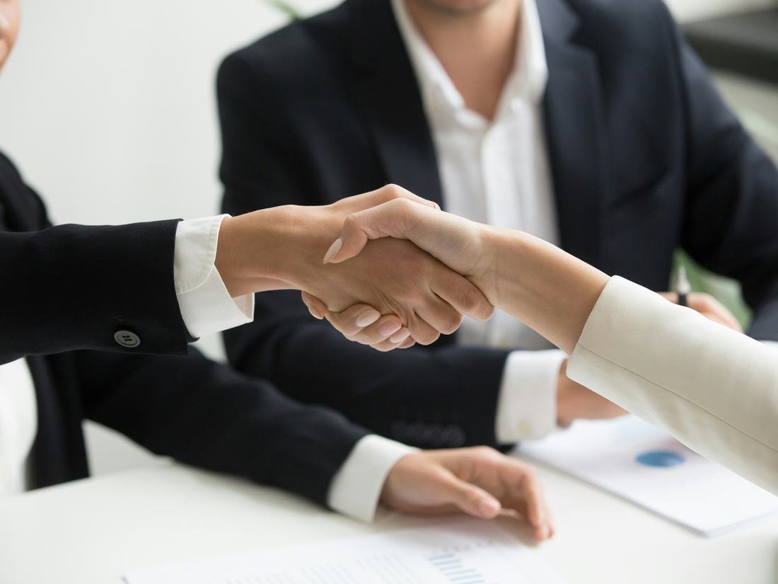 Dos personas dándose la mano tras firmar un acuerdo