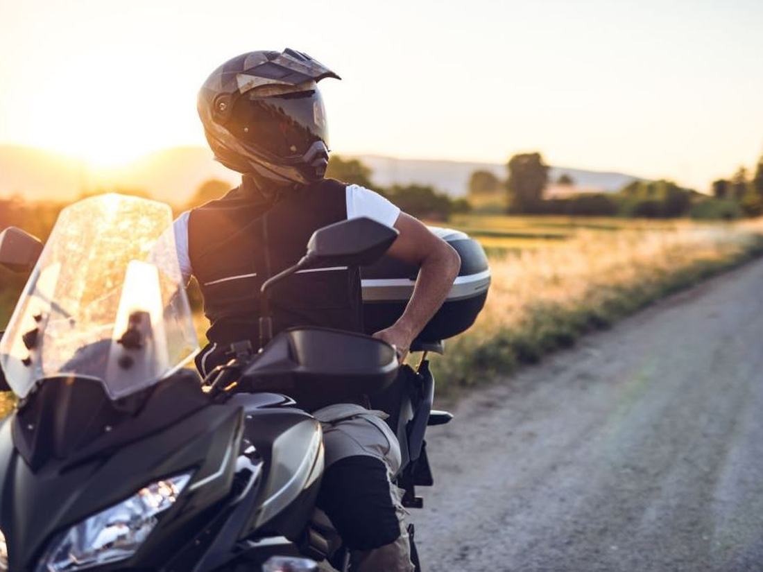 Motociclista contemplando el camino al atardecer