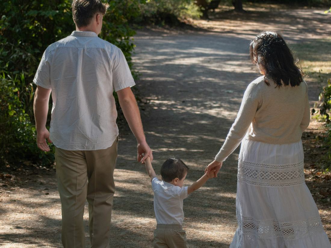 Familia caminando tomada de la mano por un sendero
